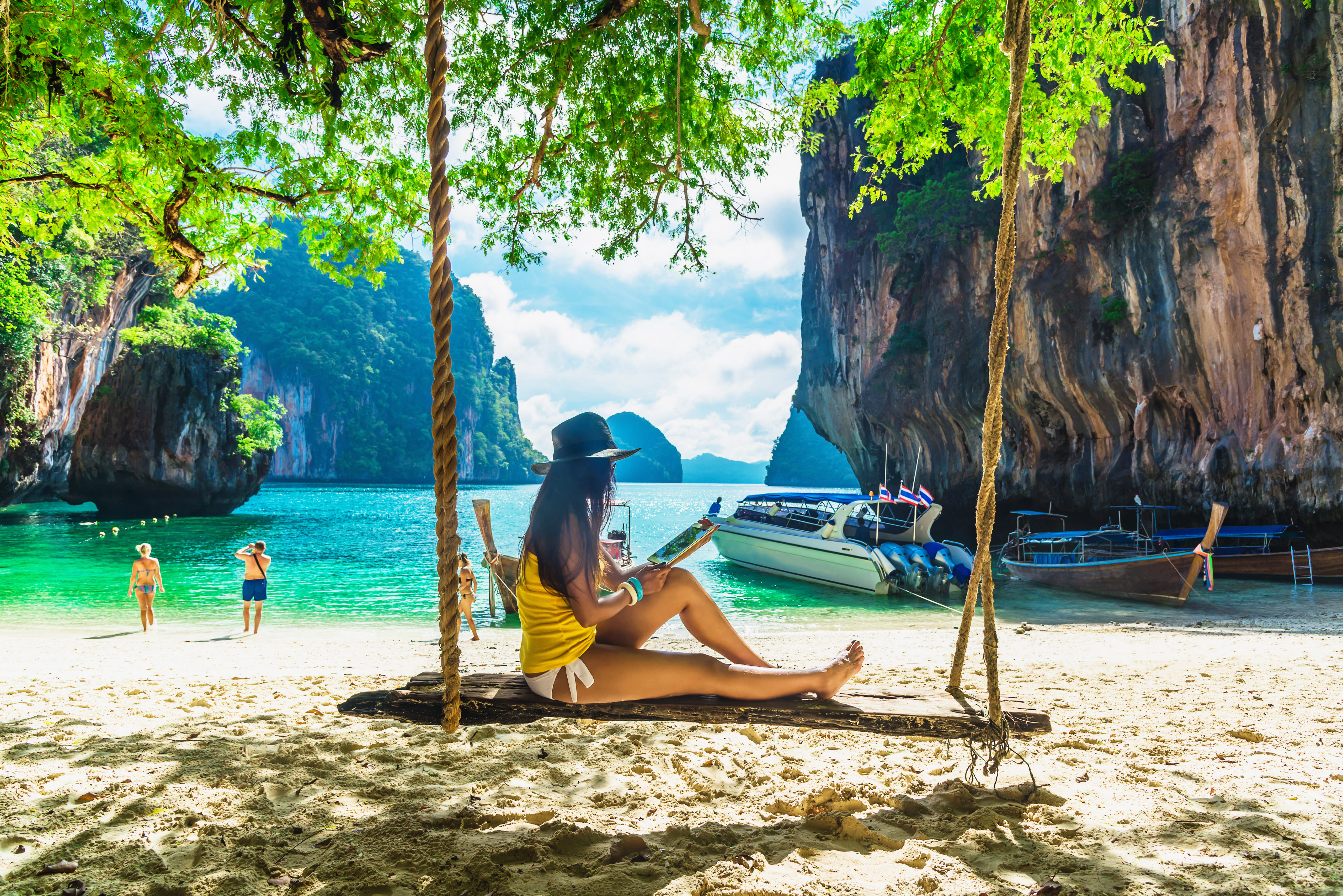 femme assise sur une balançoire et lisant un livre sur une plage en Thaïlande
